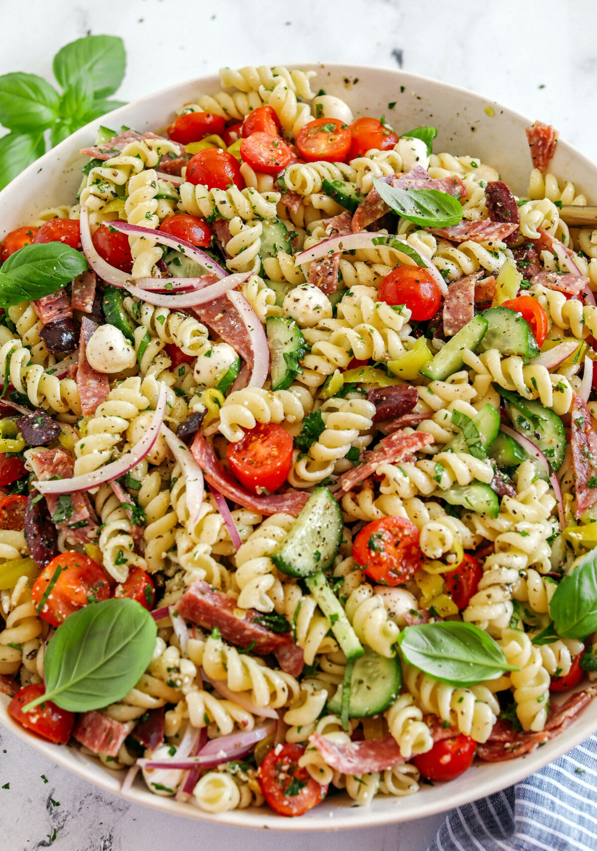 This EASY Italian Pasta Salad is loaded with juicy tomatoes, cucumbers, fresh mozzarella, spicy salami, pepperoncini, red onion and olives all tossed together with a zesty homemade Italian dressing!